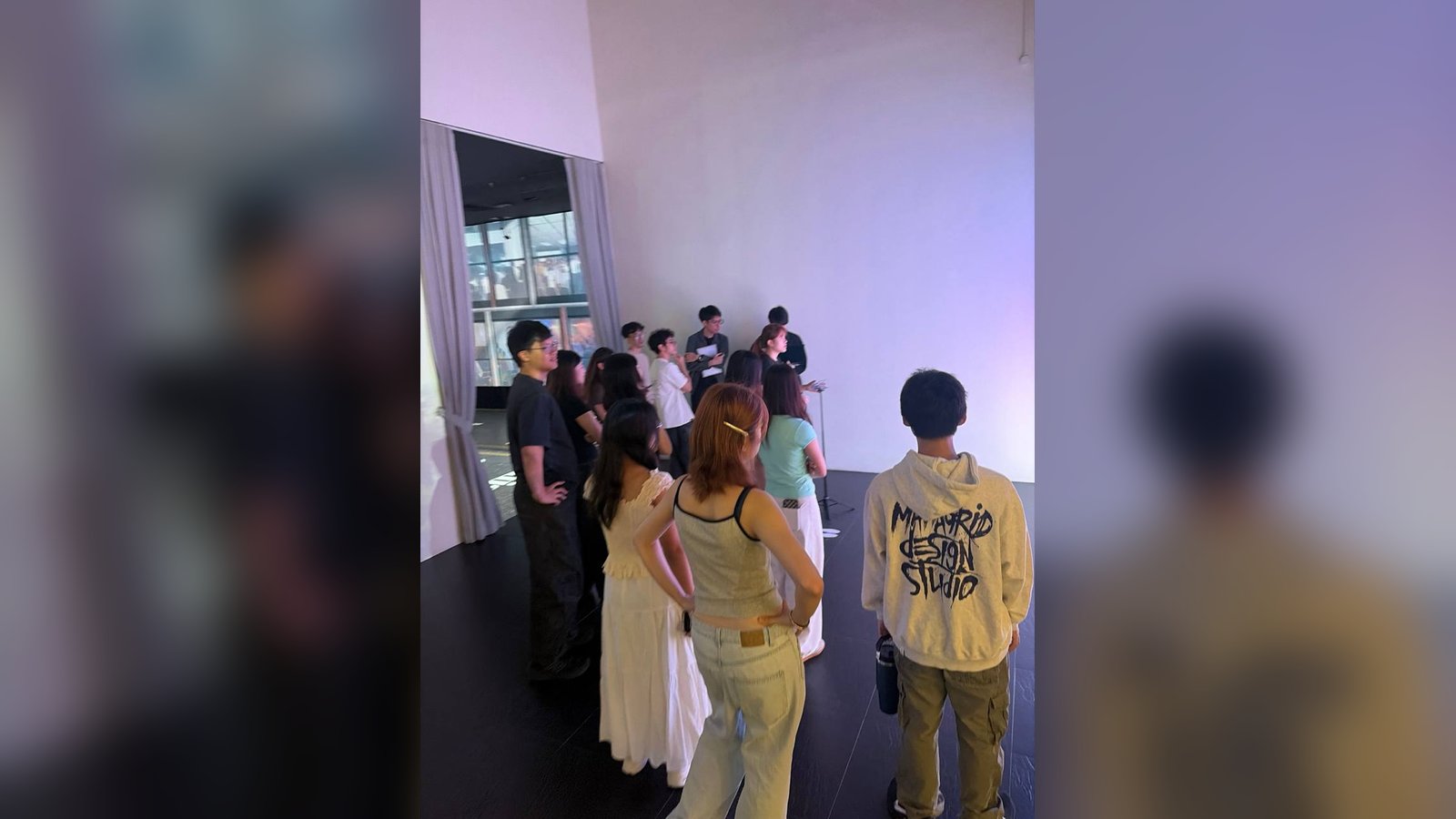 A group of people standing around the Let's Build station, with the keypad on its stand, gathering to play
