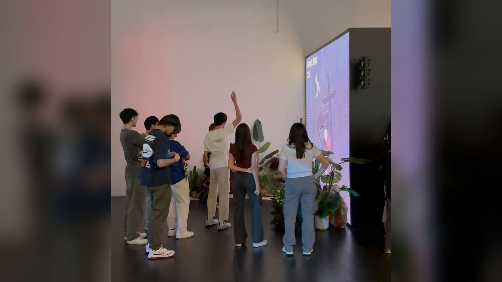 A group of people gathered in front of the LED wall while one player raises an arm to slice